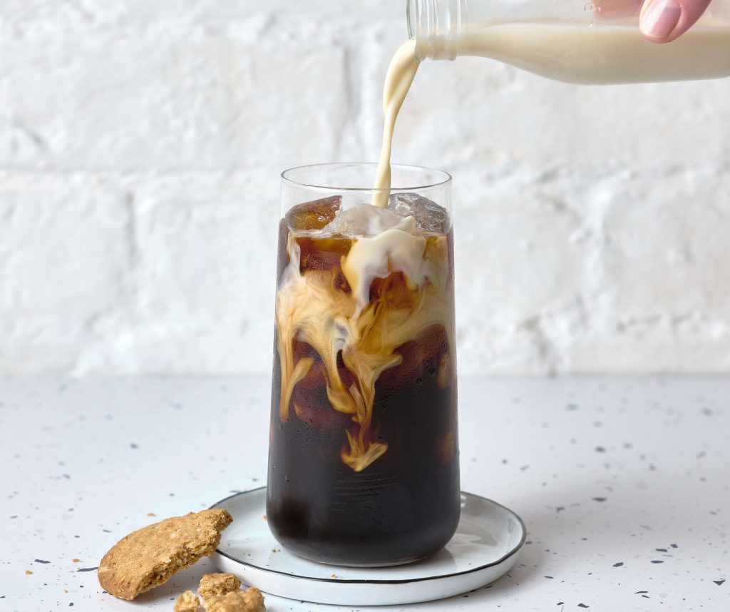 Verser du lait d'avoine dans un verre de cold brew.