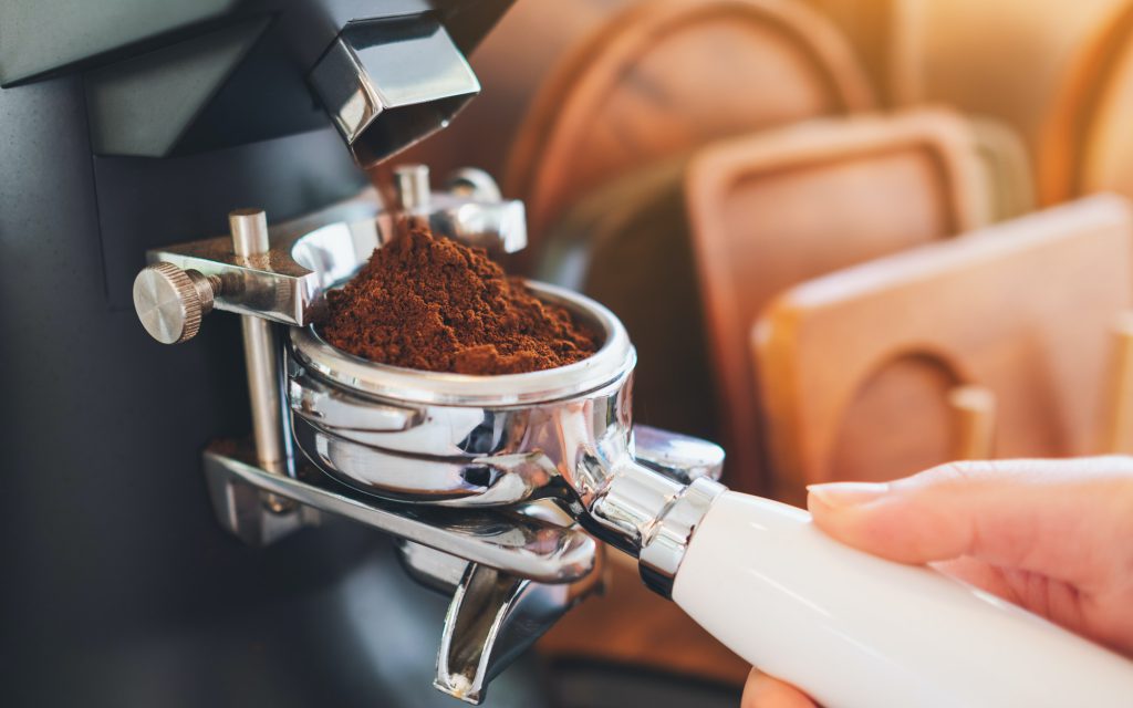 Un barista moud du café dans un portafiltre.