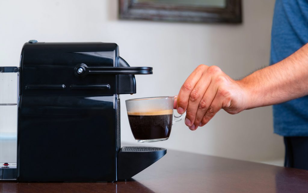 Une personne prépare du café à l'aide d'une machine à capsules.