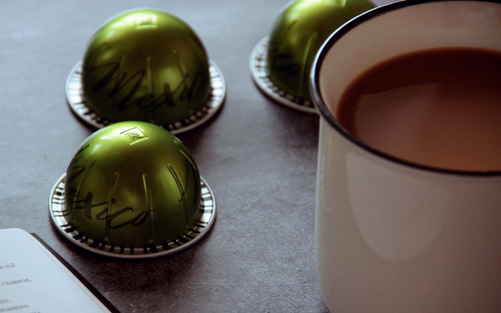 Capsules Nespresso Vertuo à côté d'une tasse de café.