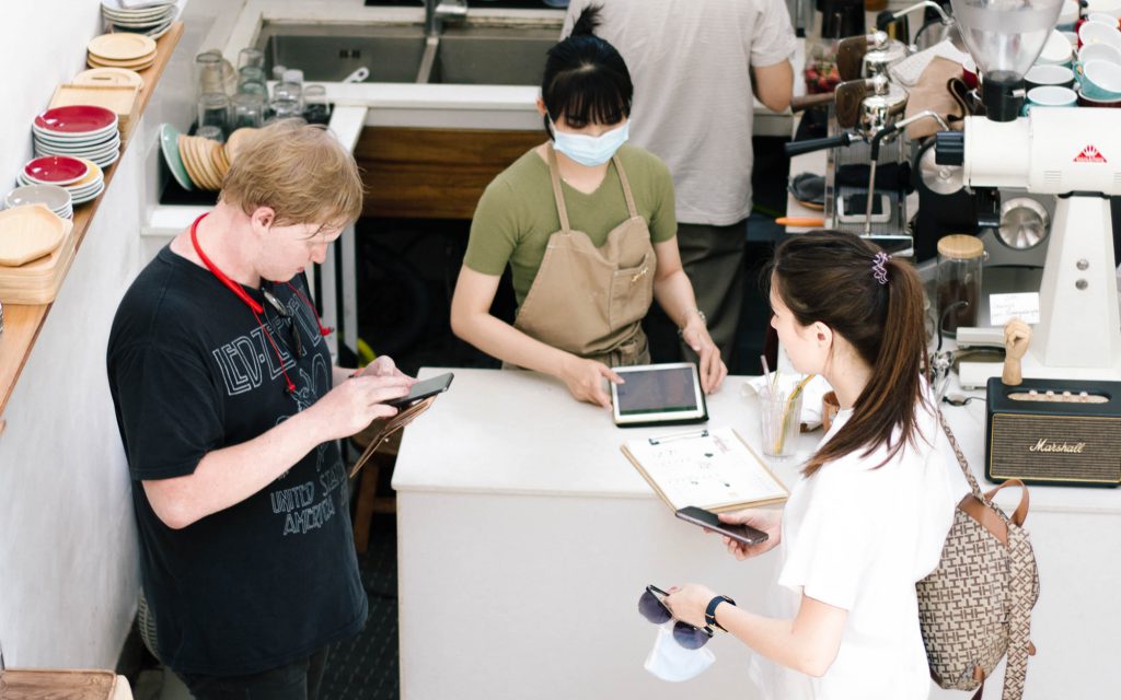 Les clients d'un café utilisent leur téléphone pour payer leur commande.