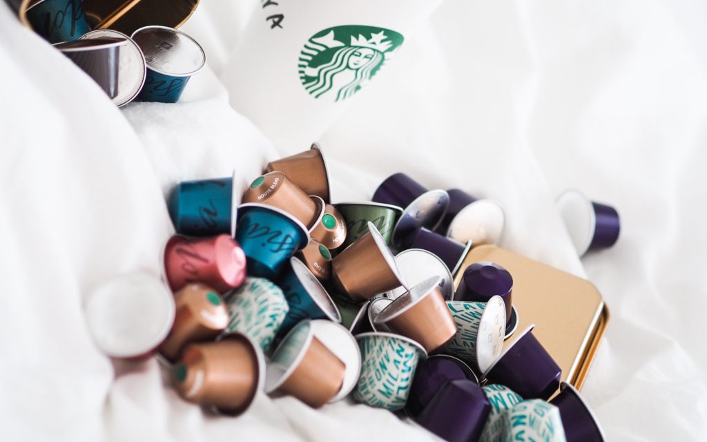 Une pile de capsules de café Starbucks à côté d'un gobelet à emporter Starbucks.